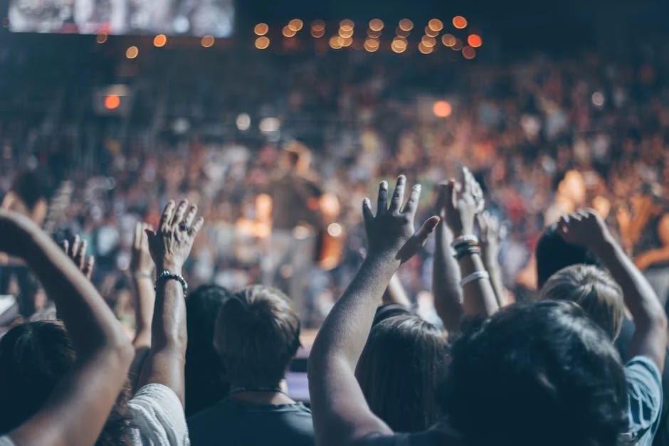 group of people lifting their arms at a concert venue 