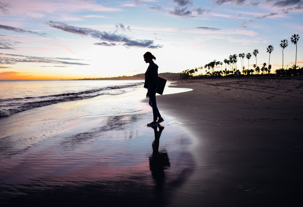 Woman standing on edge of the beach during sunset