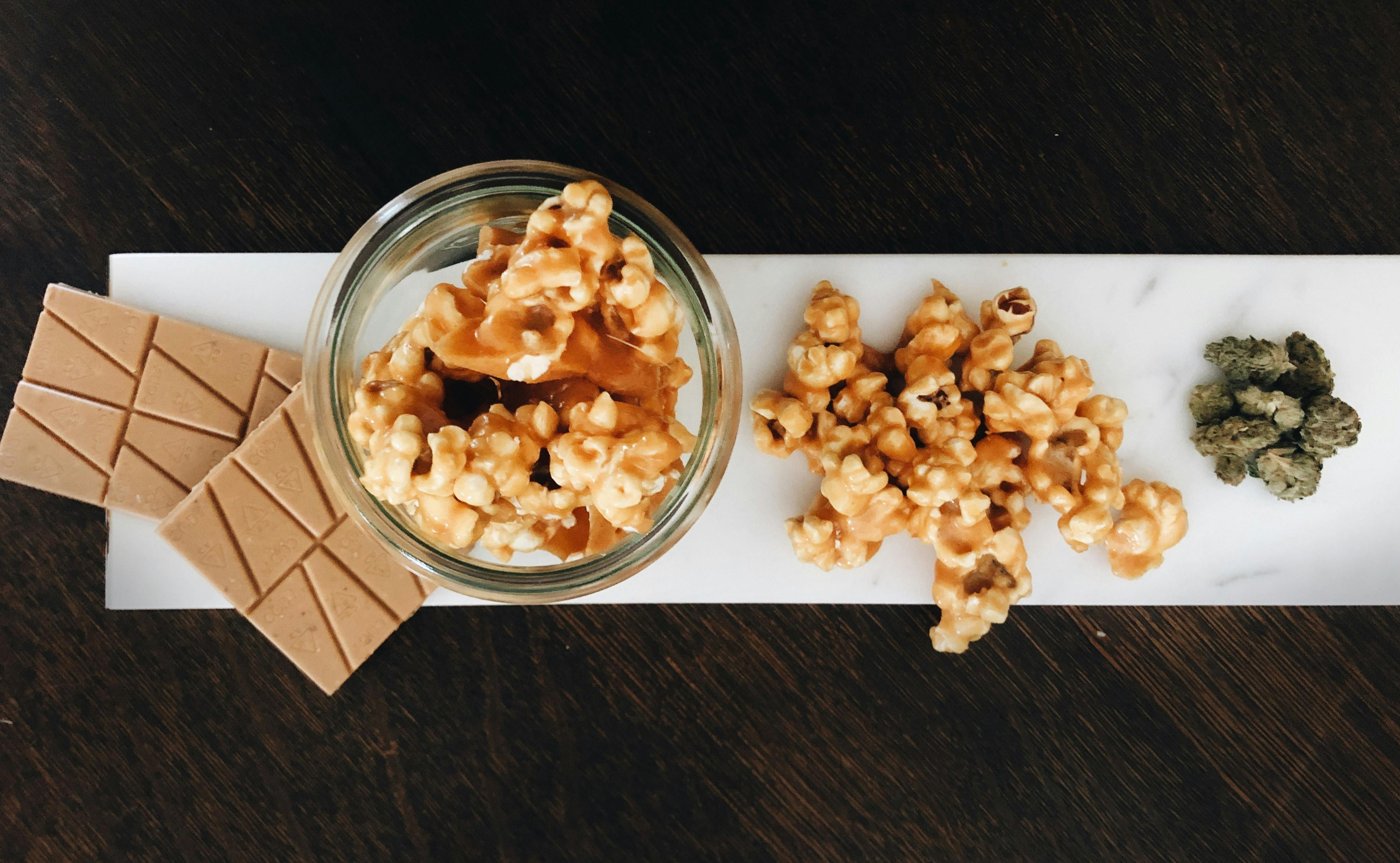 plate of weed infused spicy caramel popcorn with bars of marijuana chocolates and cannabis flower.