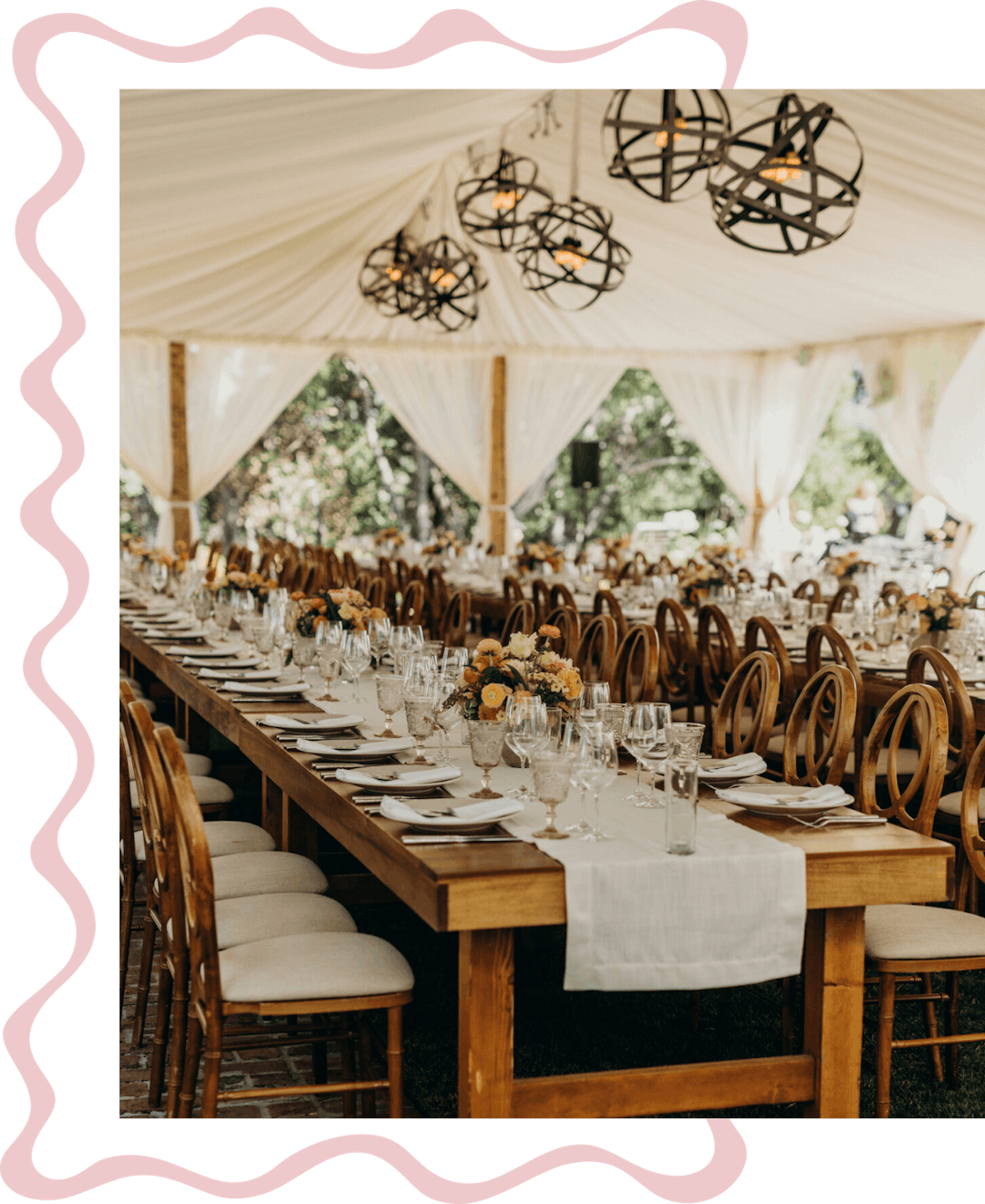 Elegant backyard wedding reception with wood tables, floral centerpieces, metal light fixtures, and tent draping.