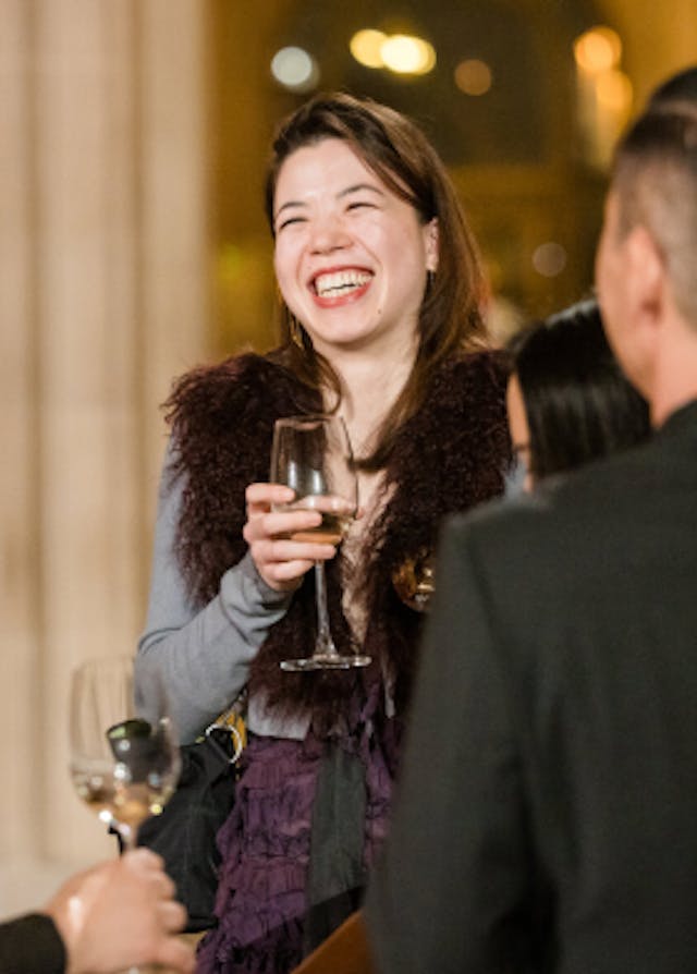 Woman smiling with glass of wine at a corporate event.