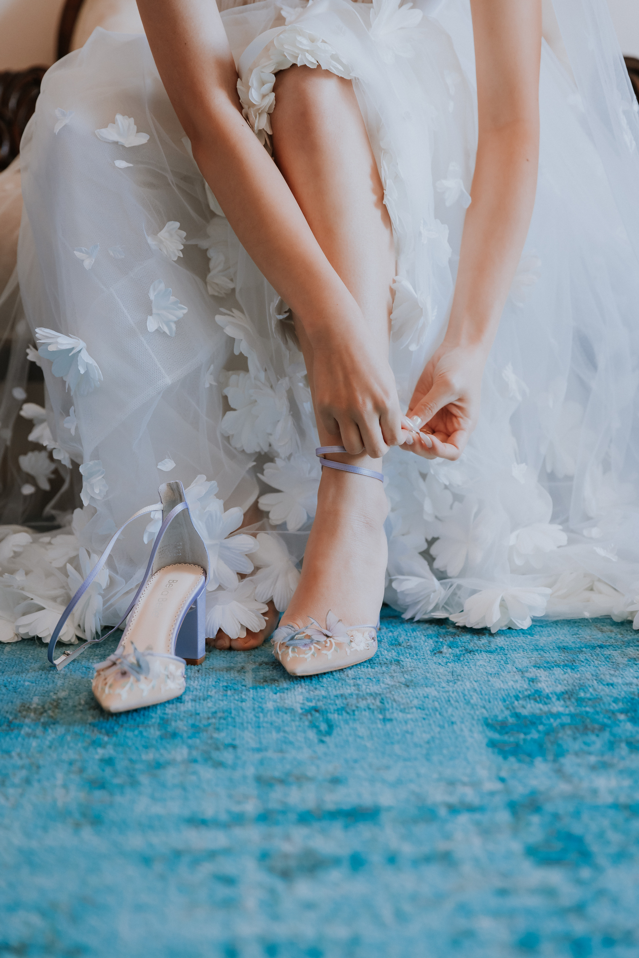Close up of a bride putting on her purple butterfly-themed  lavender heels in preparation for her wedding day.