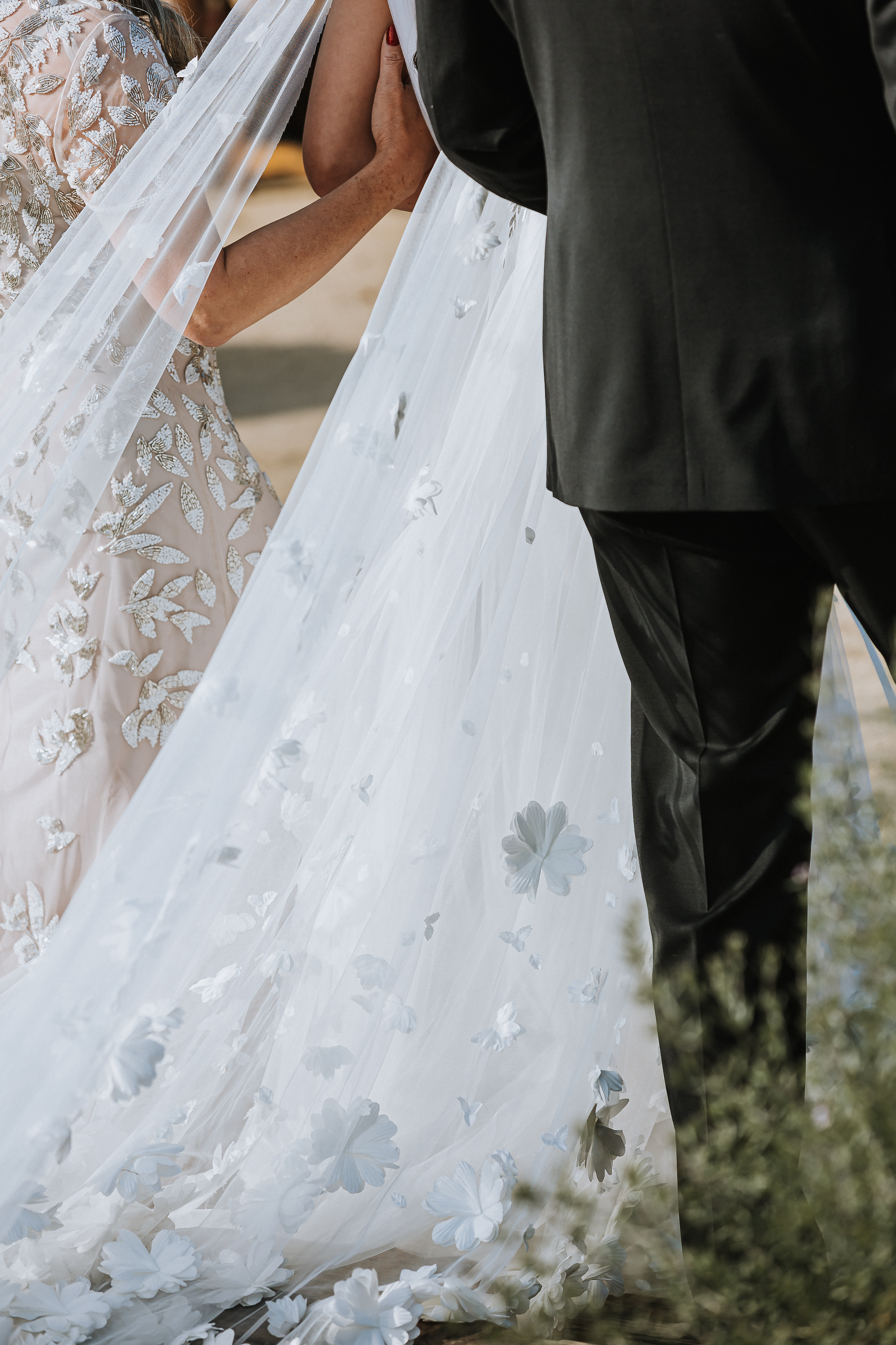 Close-up of the back of bride's dress as her parent's walk her down the aisle.