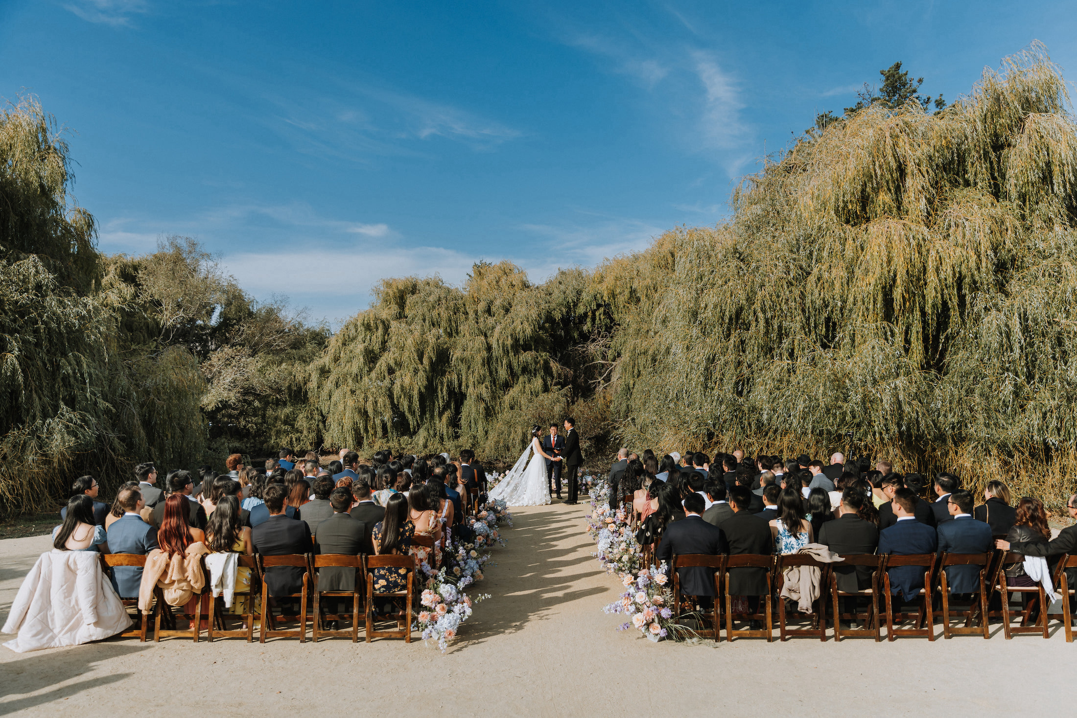 Wide shot of lakeside ceremony with bride and groom at the alter.