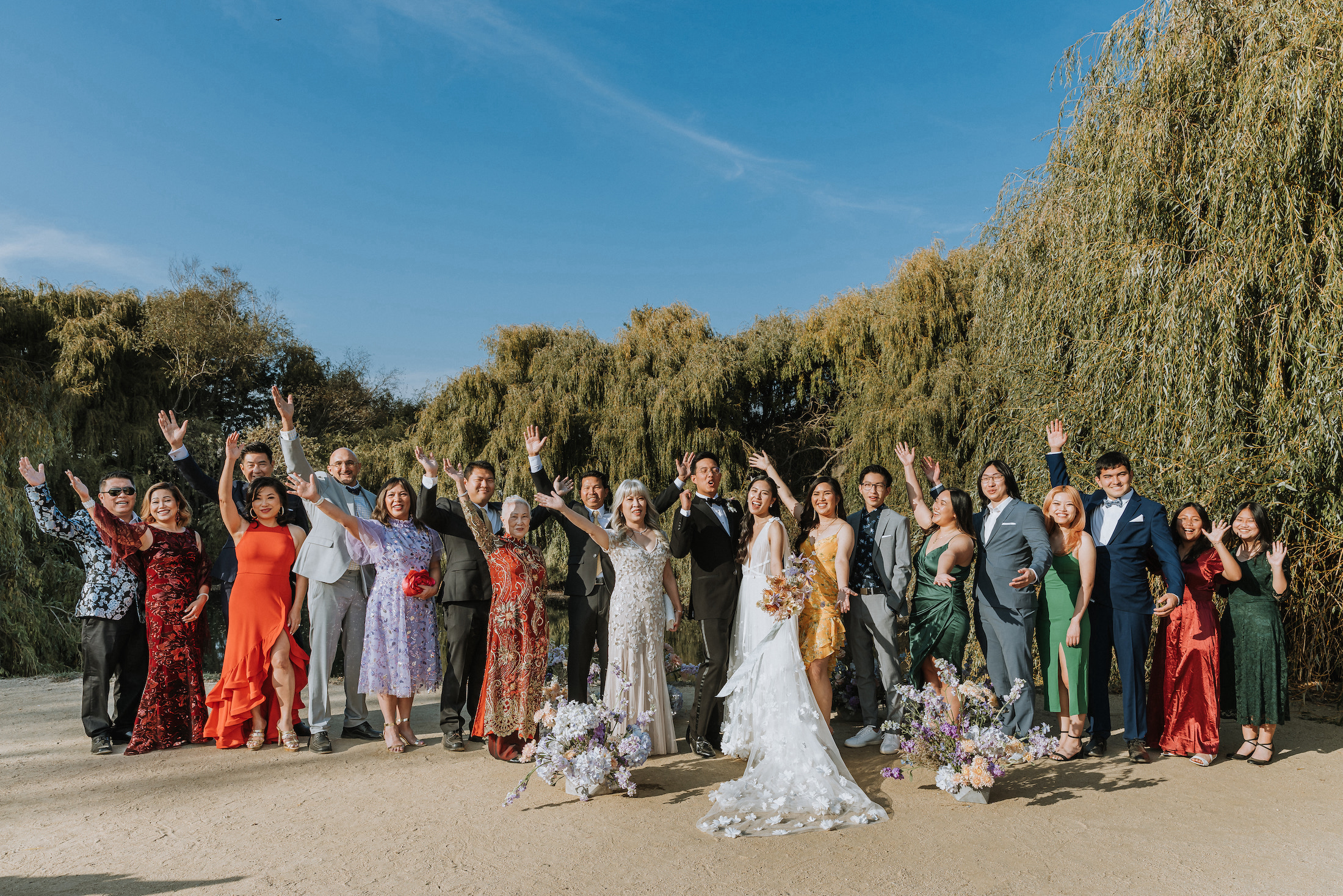 Wide shot of bride and groom with family after the ceremony raising their arms in celebration. 