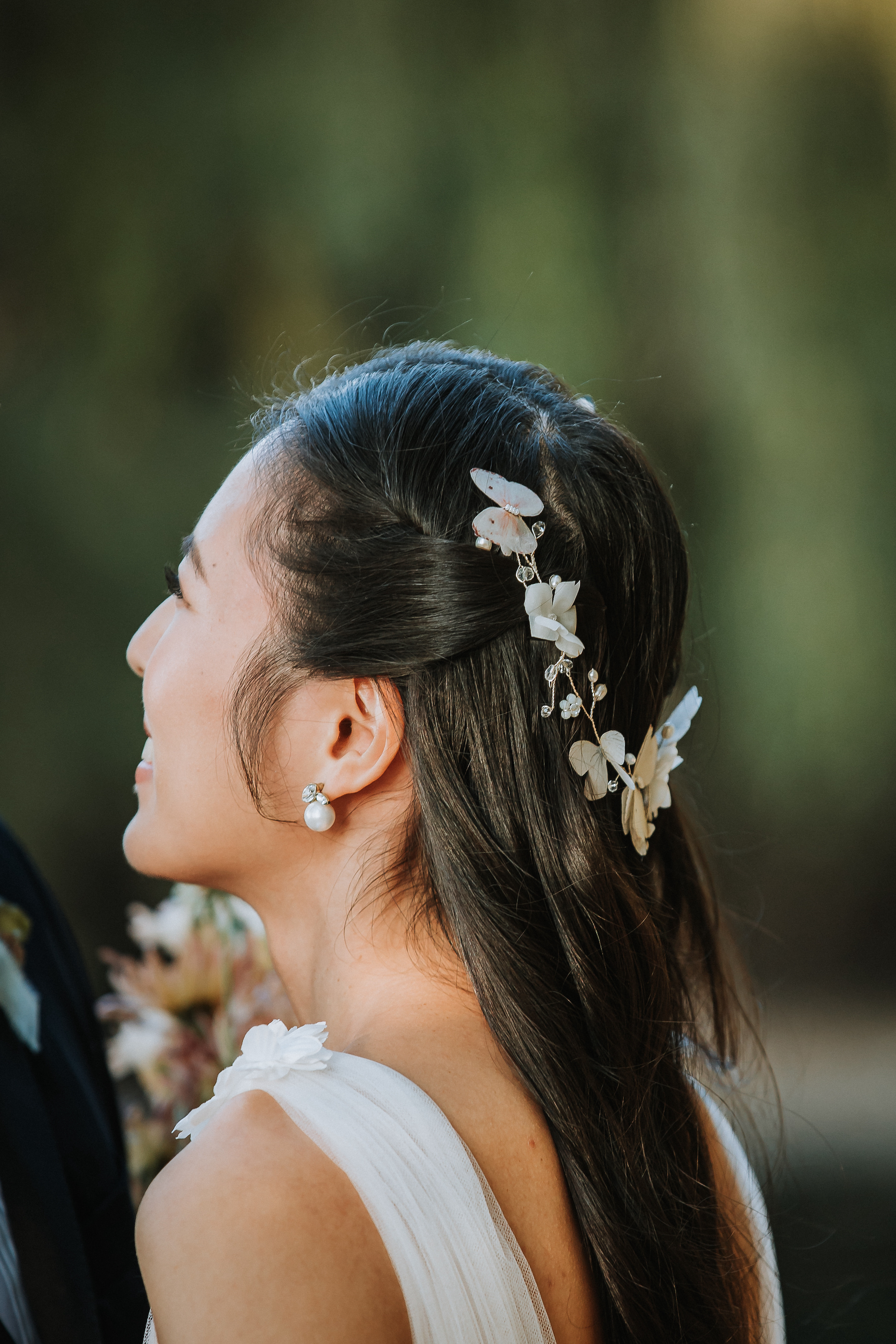 Close-up of bride showing her pearl earrings and butterfly hairpiece. 