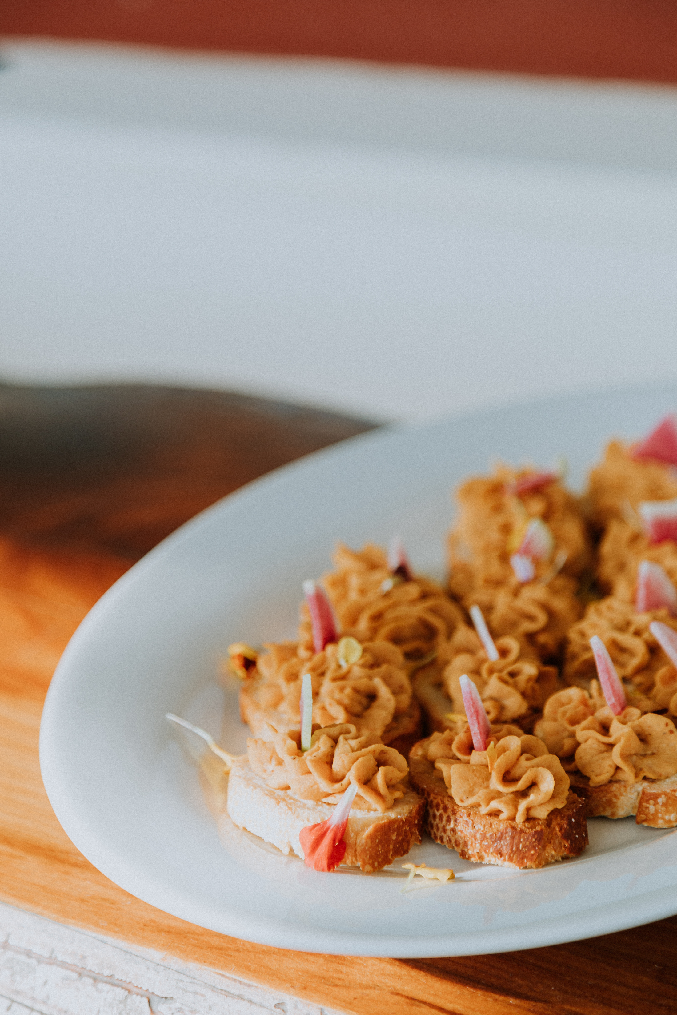 A plate of crostinis topped with chickpea puree and watermelon radish. 