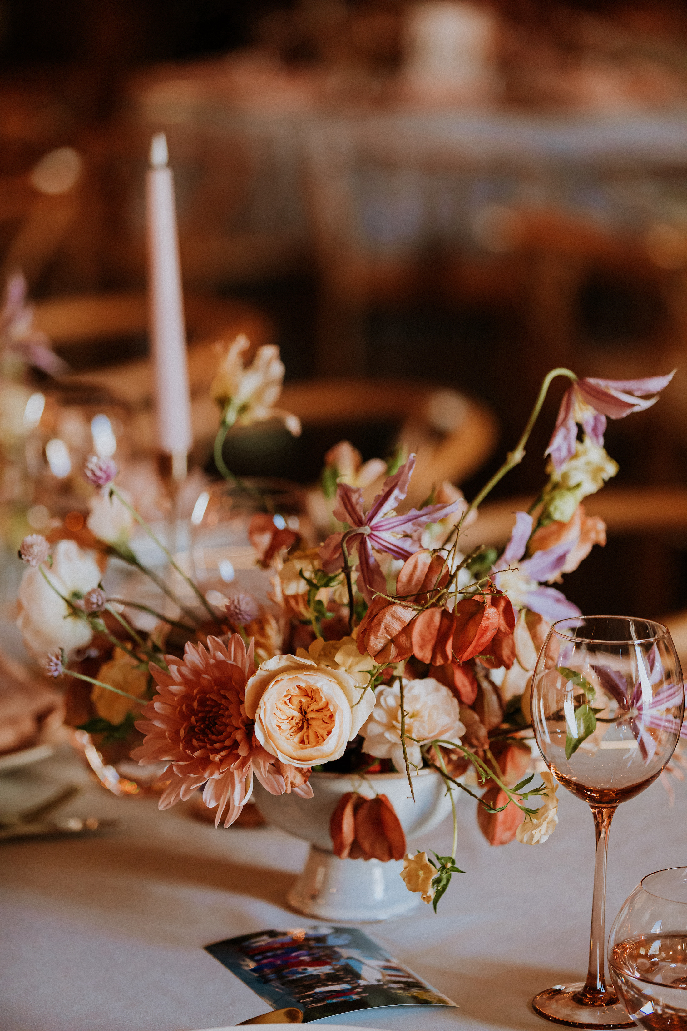 Close-up of peach, lavender, and white colored floral arrangement on table.