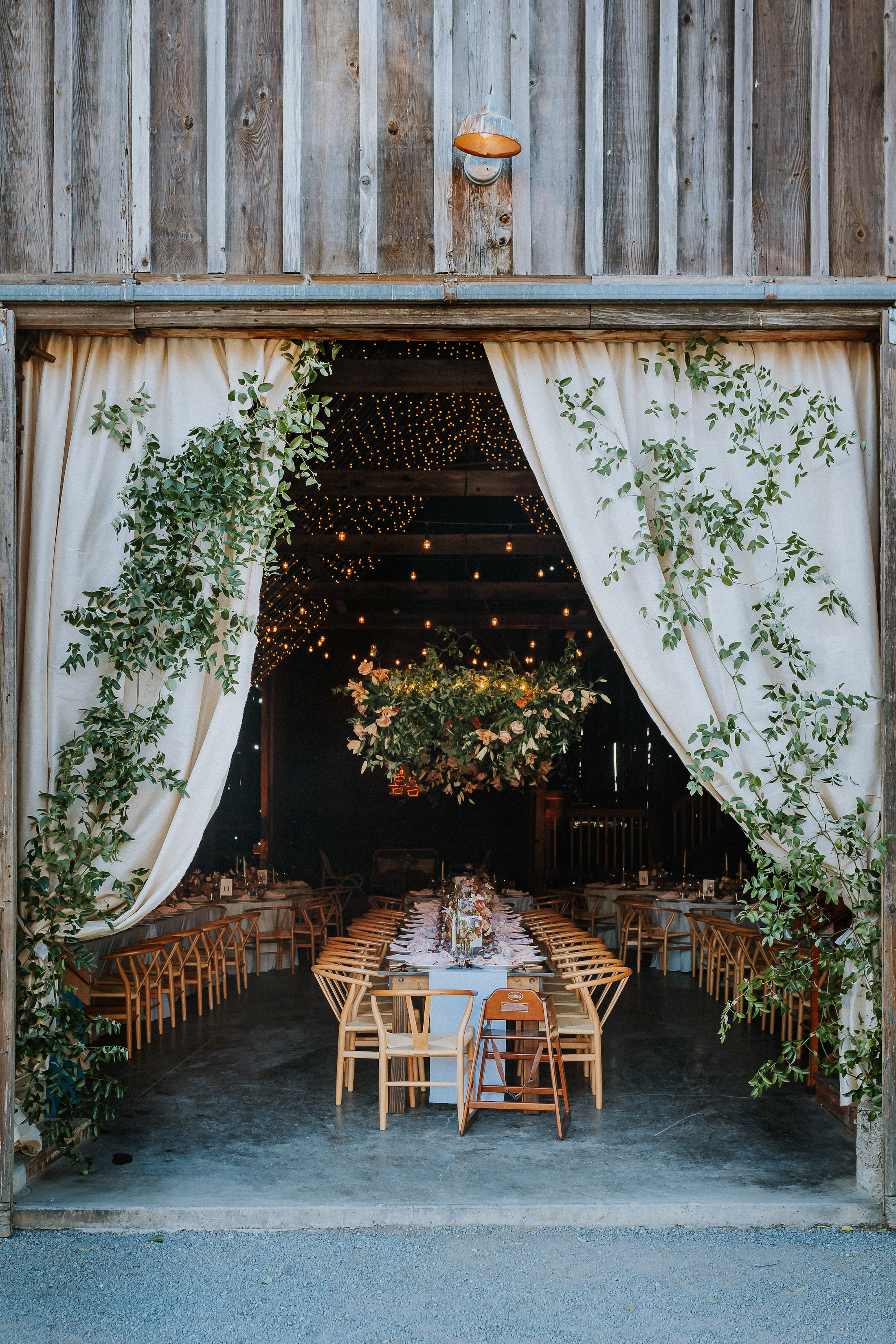 A charming barn wedding reception adorned with lush greenery, colorful flowers, and twinkle lights.