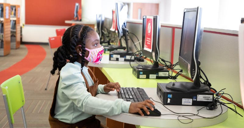 Girl wearing a mask and using a library computer