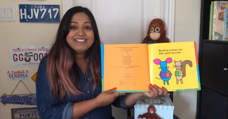 Librarian holding book Reading Makes You Feel Good, by Todd Parr