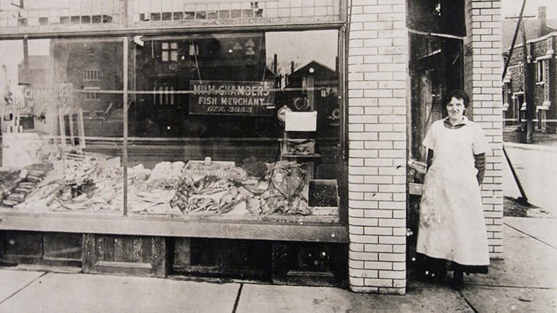 Vintage photo of woman in apron outside of shop