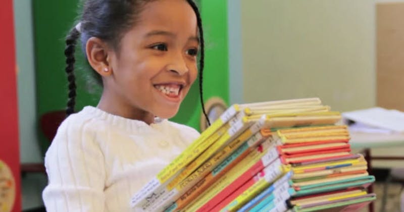 Smiling child carrying a stack of books