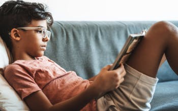 A boy reading on a couch.