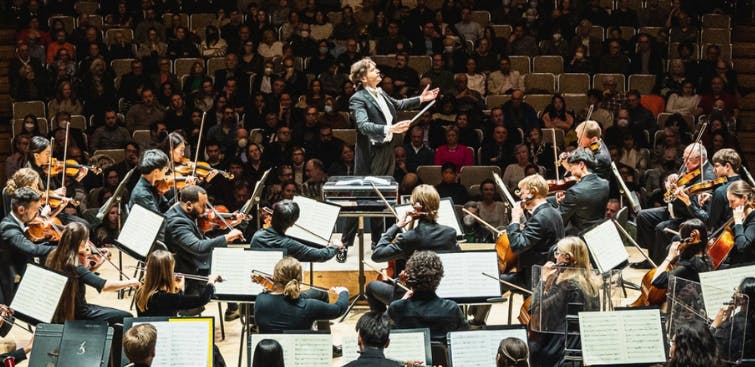 Interior view of the Toronto Symphony Orchestra performing with a conductor.