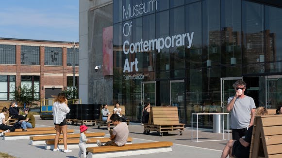 People sit and stand outside of the entrance to the Museum of Contemporary Art.