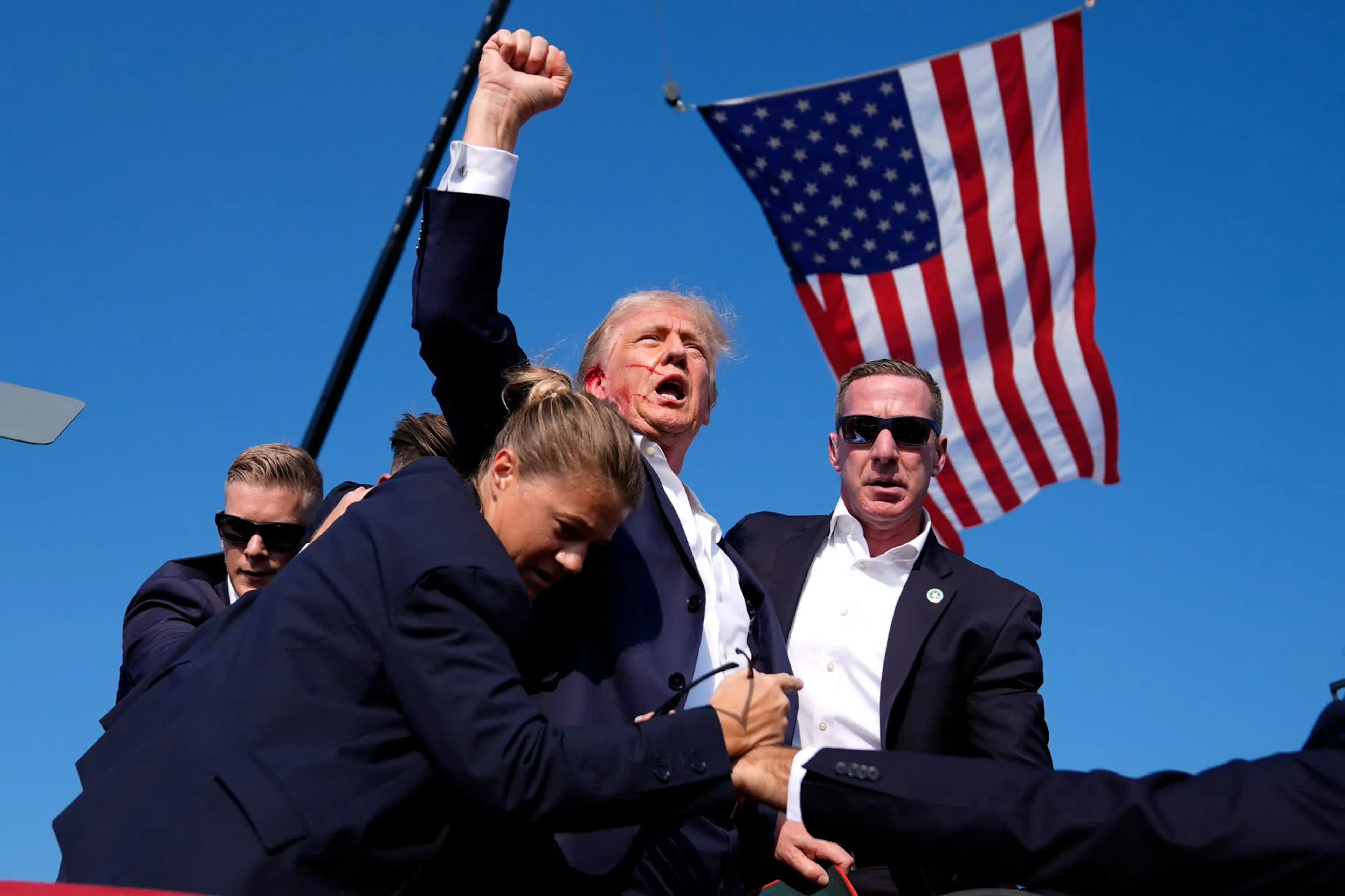 conic image of the bloodied former President, his fist raised, standing in front of an American flag.