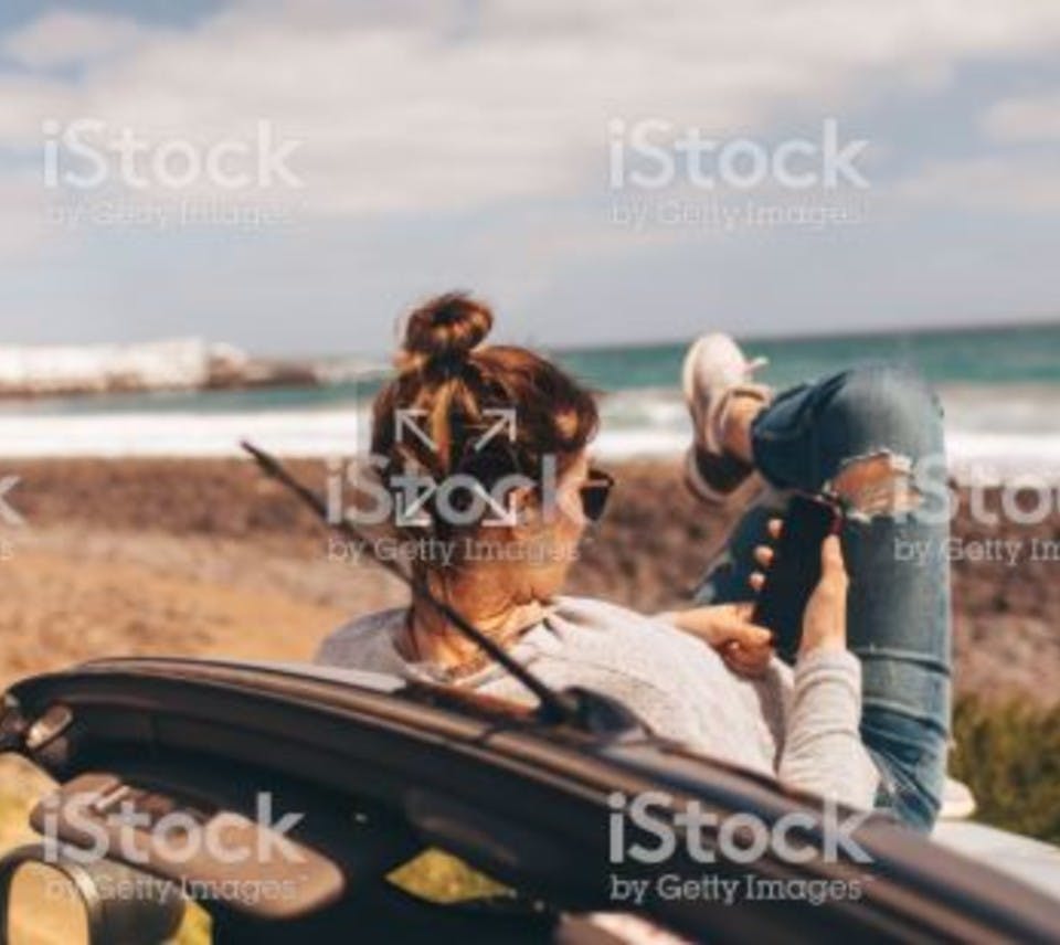 Woman trading on her mobile by the beach