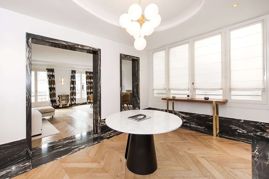 Vue sur le salon depuis le vestibule de cet appartement luxueux en marbre et parquet massif