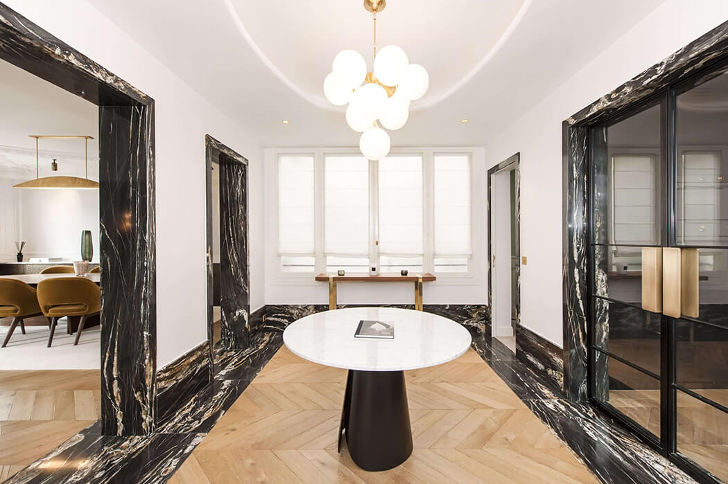 vestibule avec déco haut de gamme mêlant marbre, parquet à chevrons et accessoires design