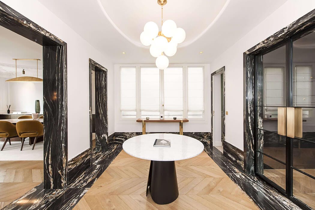 vestibule avec déco haut de gamme mêlant marbre, parquet à chevrons et accessoires design