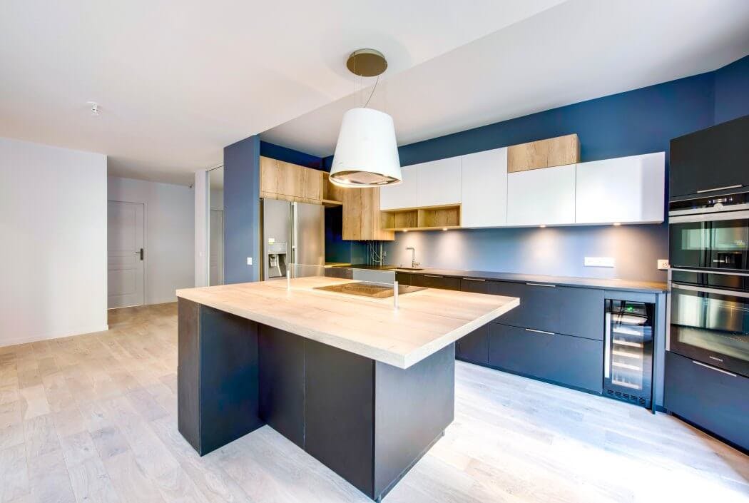 Zoom sur l'îlot central de cette cuisine haut de gamme et très design mêlant gris et bois massif