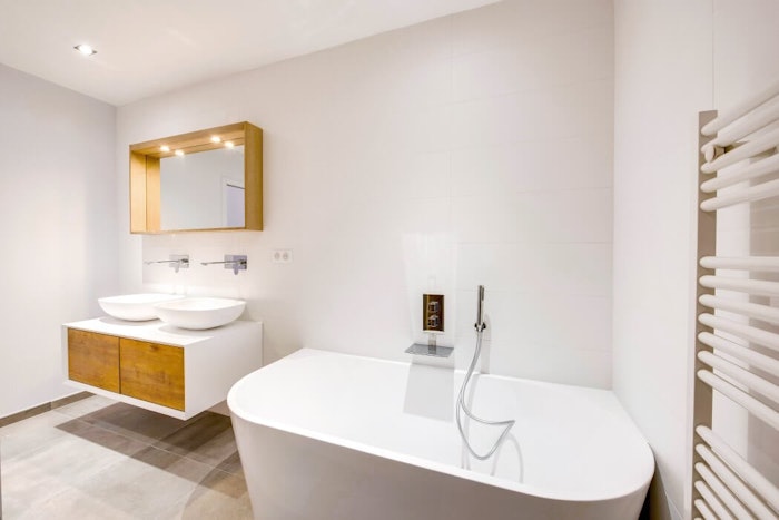 Salle de bain blanche avec double vasque et baignoire aux angles arrondis