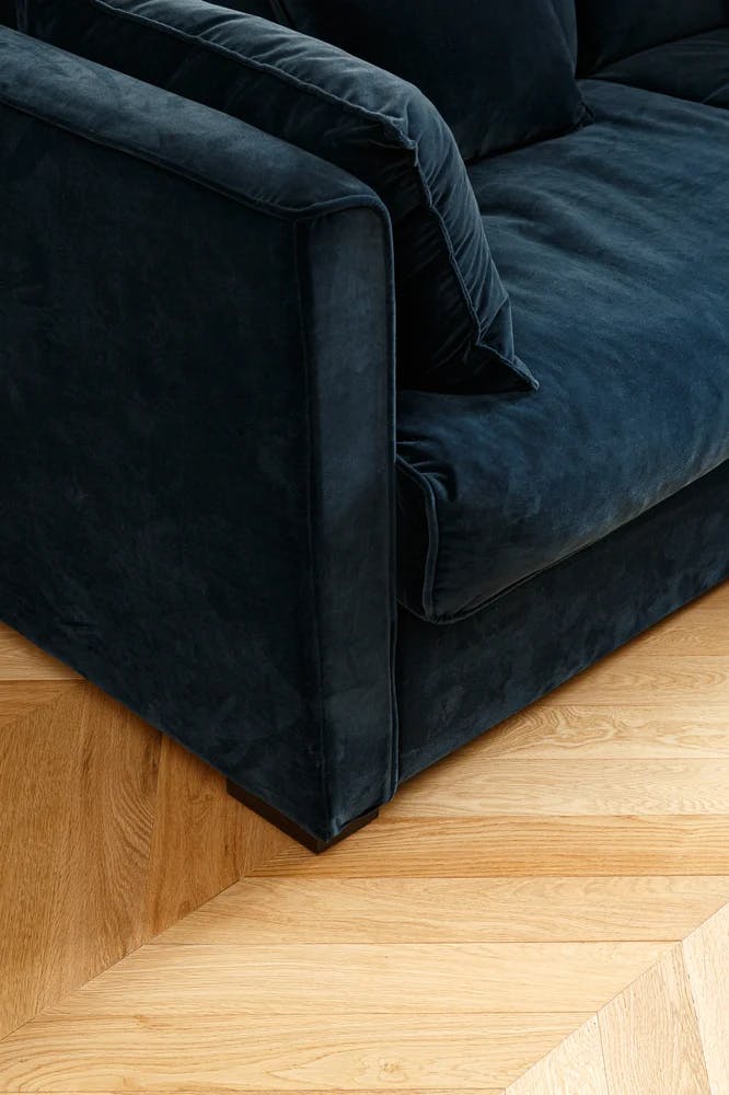 Canapé en velours bleu nuit et parquet stratifié