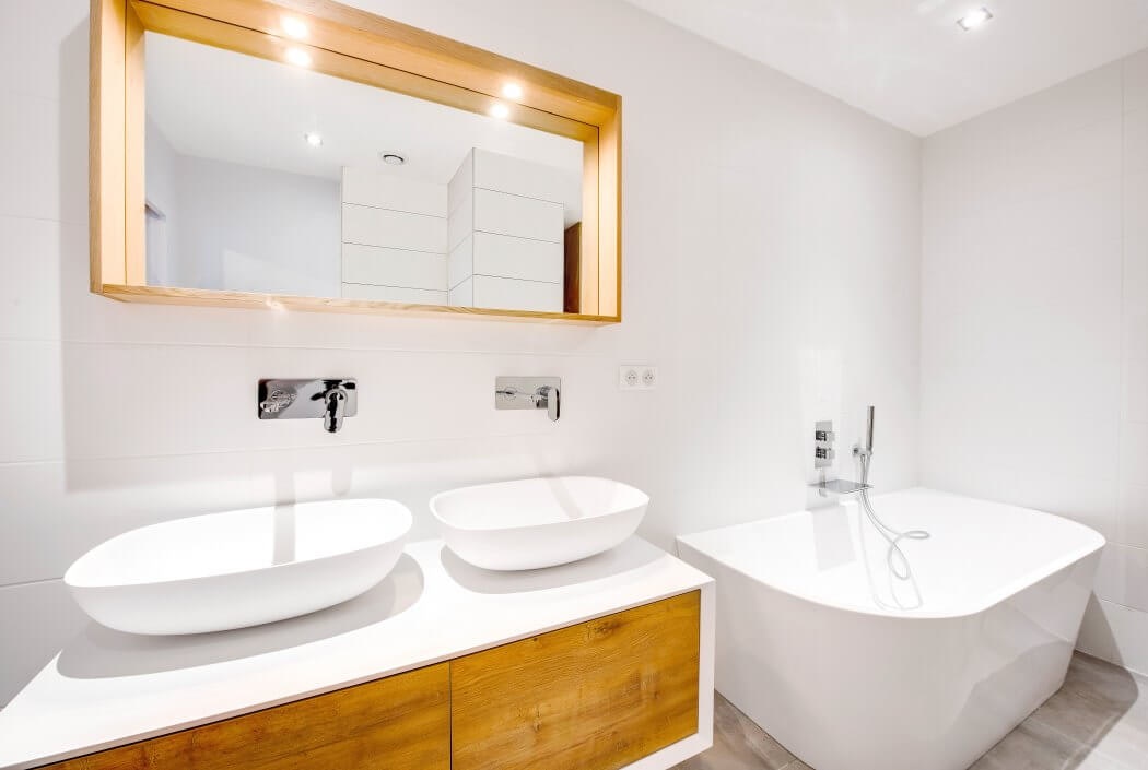 Salle de bain tons naturels (blanc, bois et gris) avec lavabos aux formes arrondies rappelant celles de la baignoire