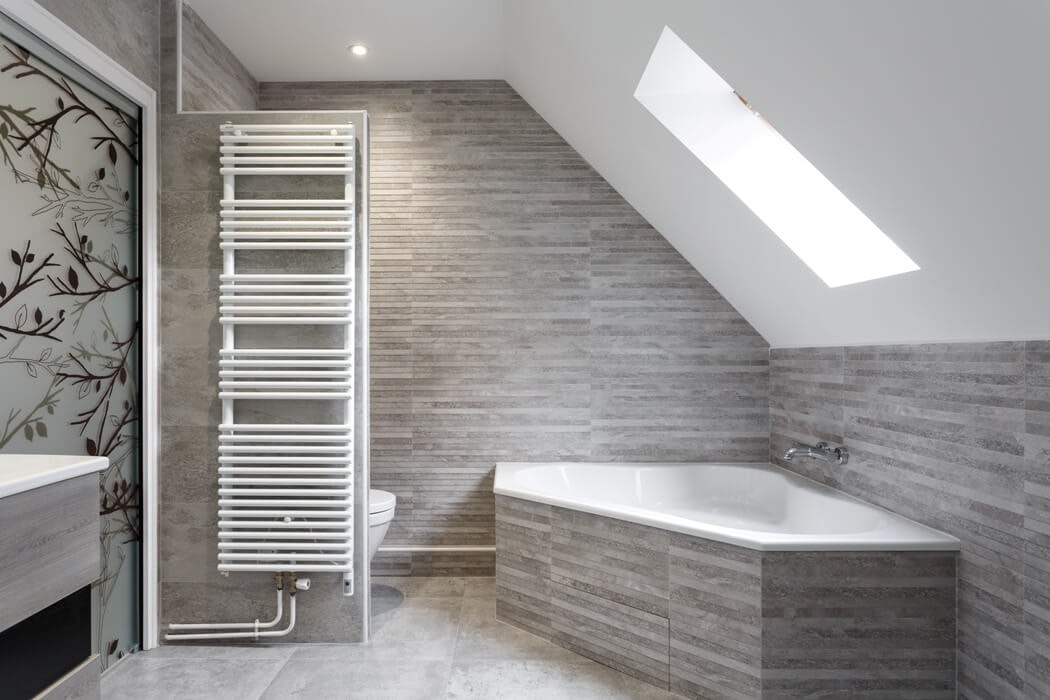 Une belle baignoire d'angle aux tons gris dans cette salle de bain rénovée