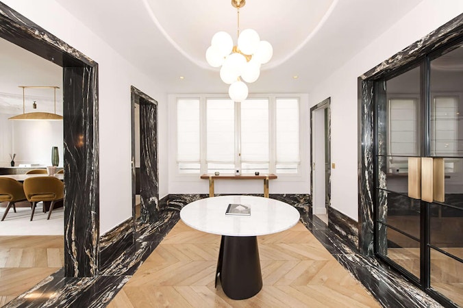 vestibule avec déco haut de gamme mêlant marbre, parquet à chevrons et accessoires design