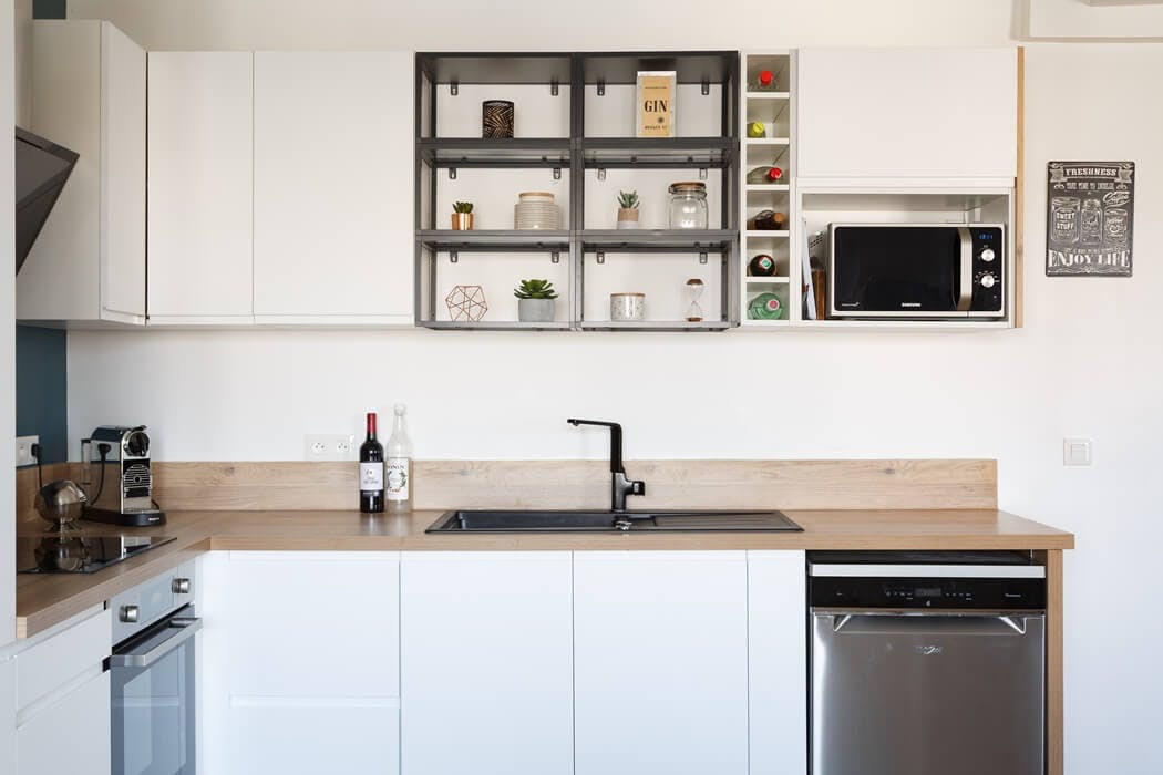 Zoom sur la cuisine blanche, son plan de travail en bois massif, et ses nombreux rangements