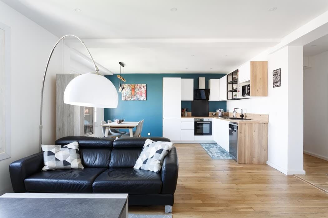 Cuisine ouverte sur le salon avec un mur vert canard et un joli parquet massif