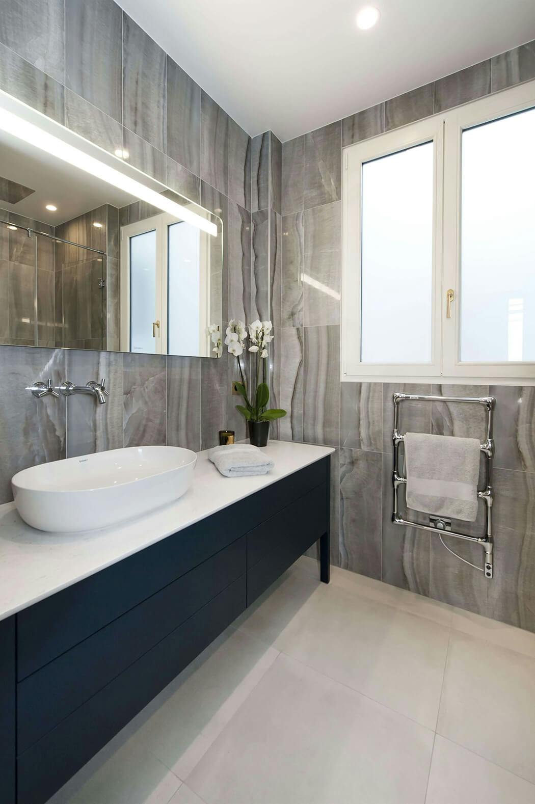 salle de bain de luxe entièrement rénovée avec grand miroir, marbre aux murs et meuble sous vasque anthracite