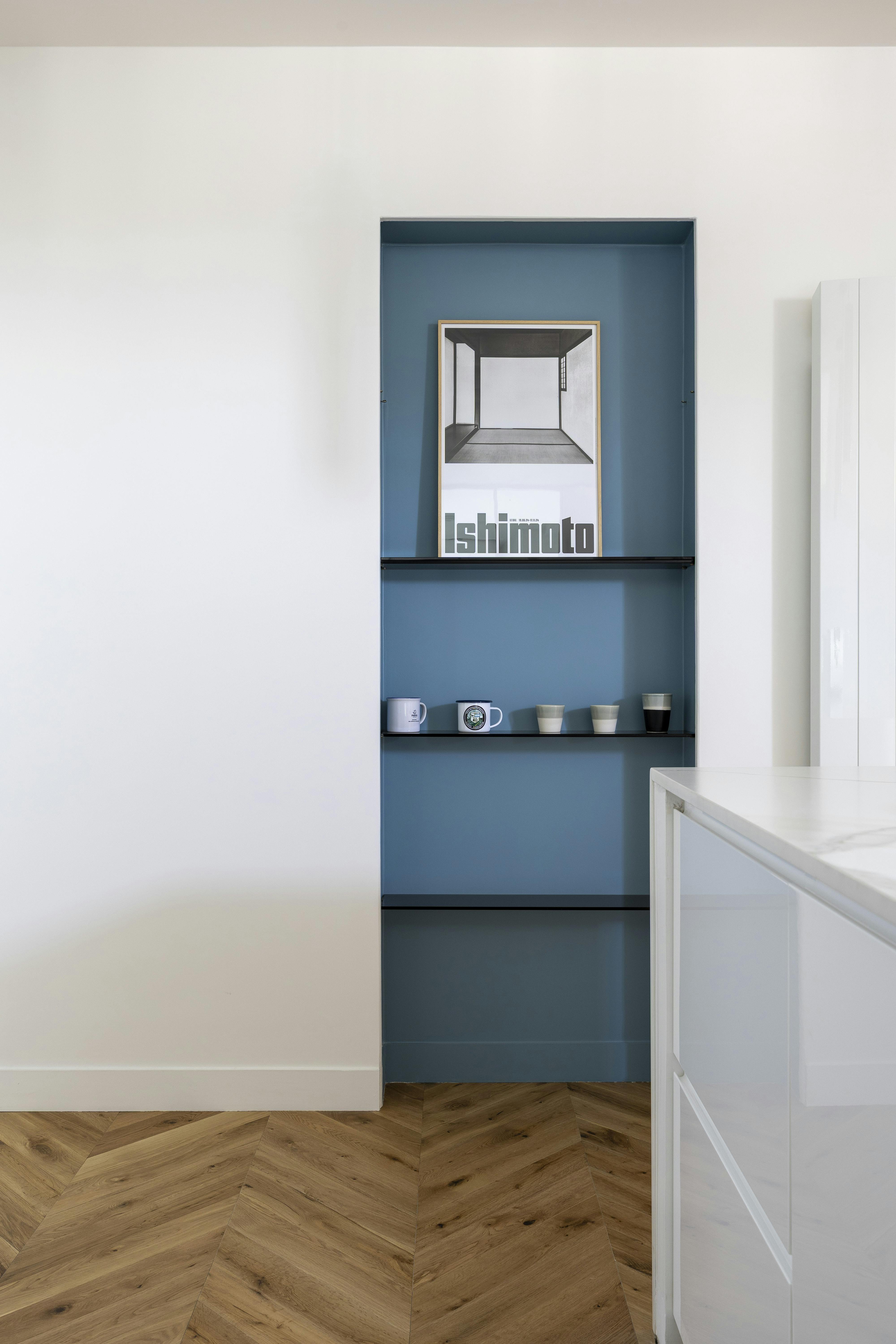 Niche murale bleu pastel avec étagères fines.