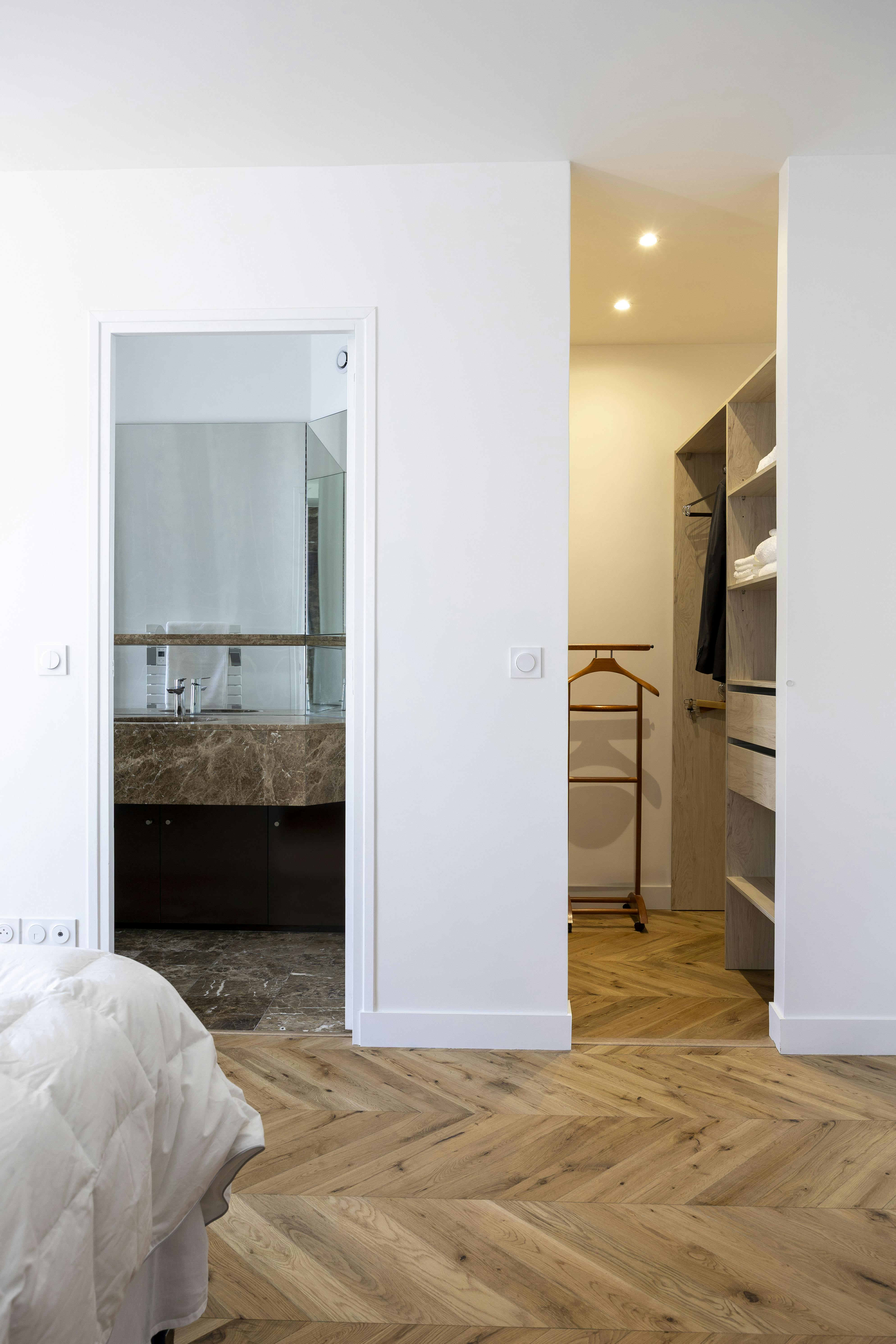 Suite parentale raffinée avec accès direct à une salle de bain en marbre marron et un dressing.