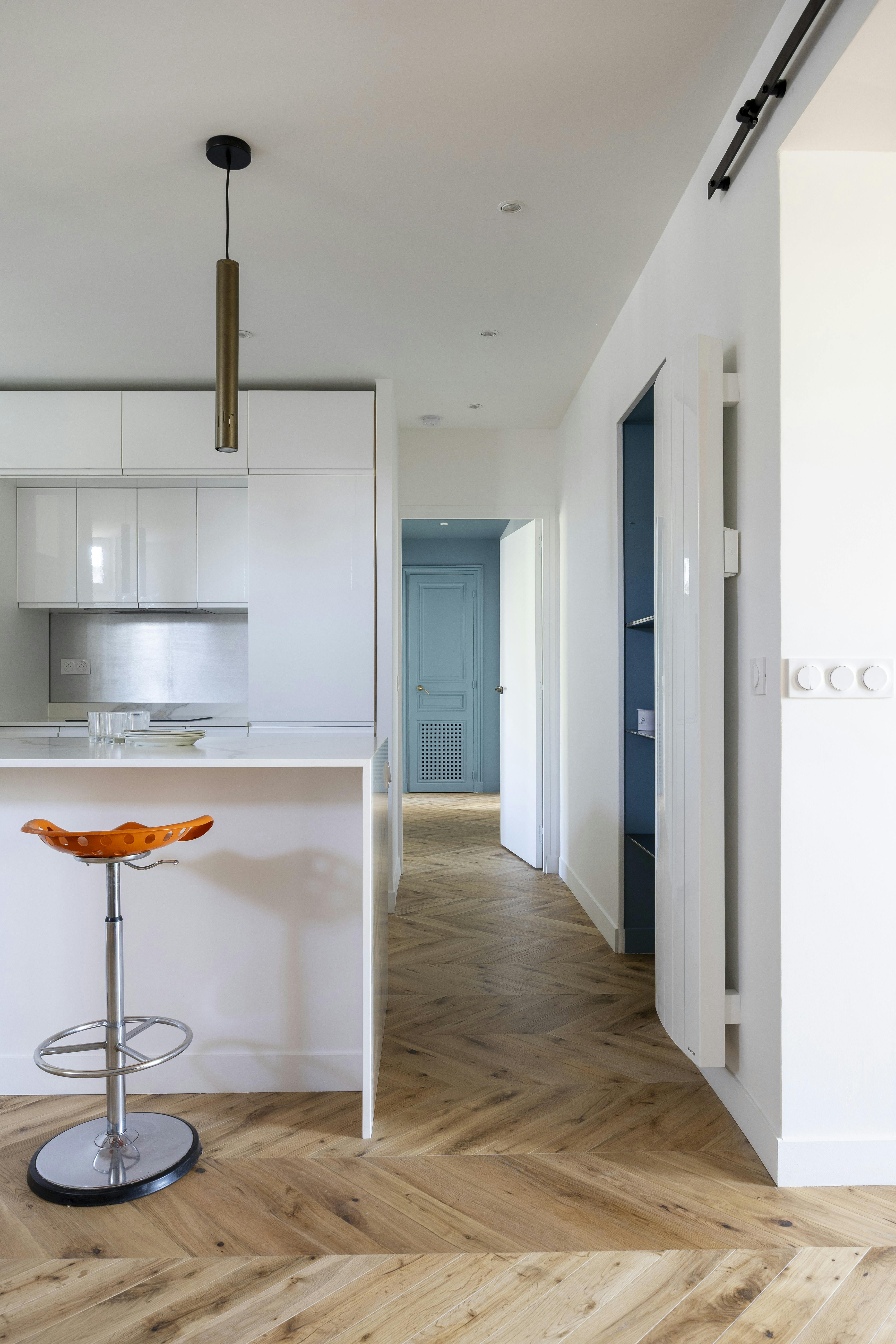 Cuisine ouverte moderne avec vue sur un couloir élégant avec un fond bleu pastel.