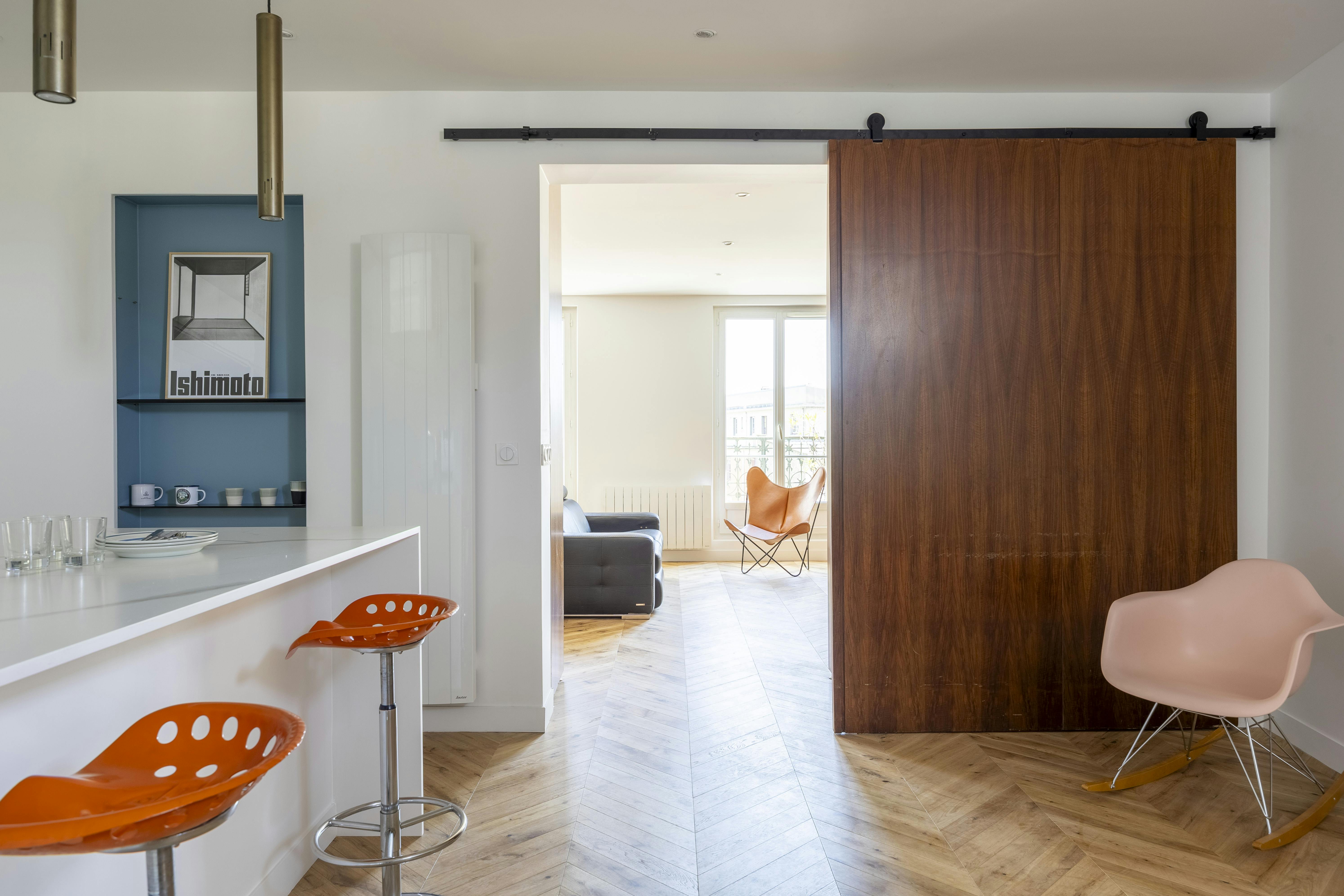 Cuisine contemporaine séparée du salon par une grande porte coulissante en bois.