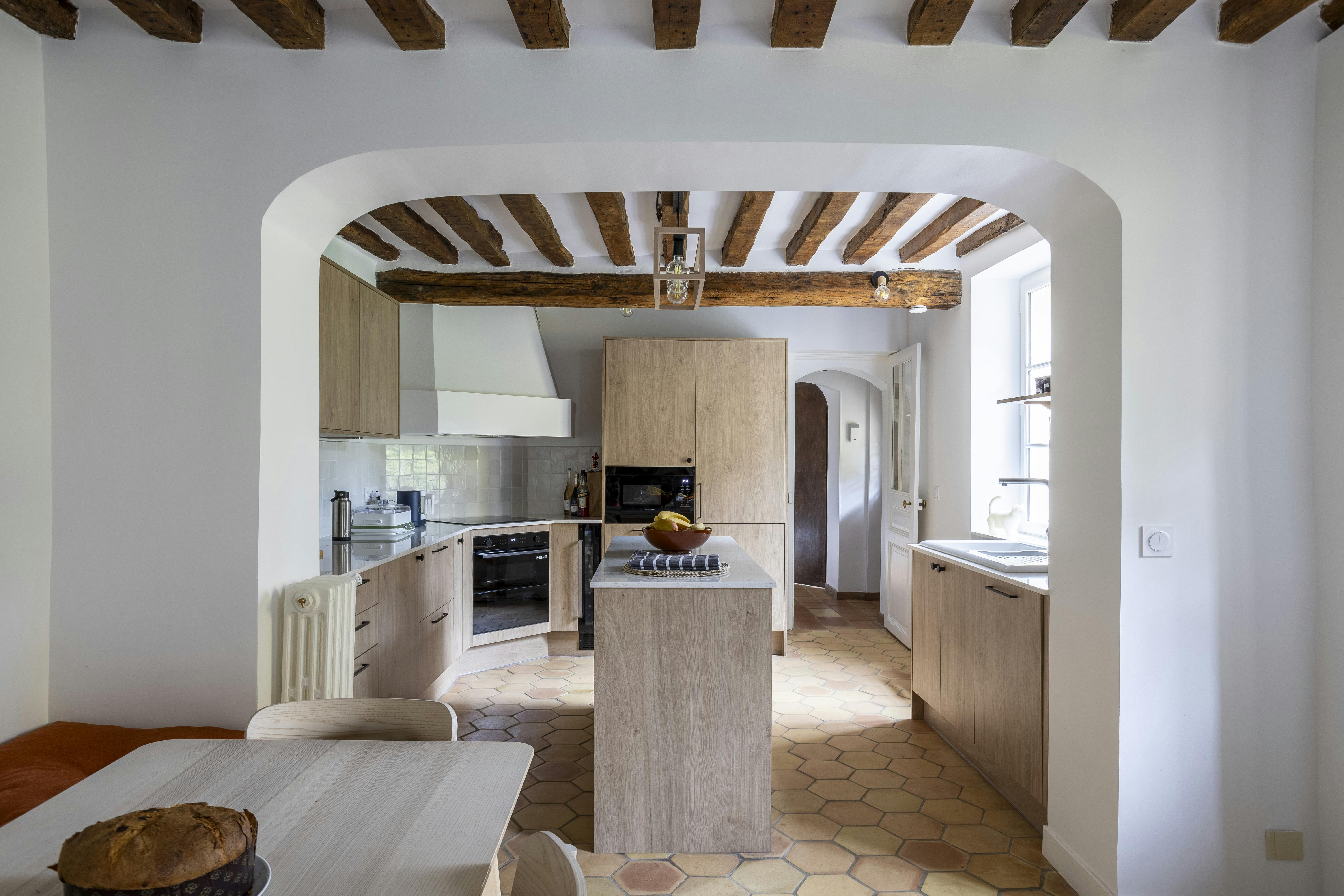 Une cuisine chaleureuse avec des éléments en bois naturel et un îlot central.