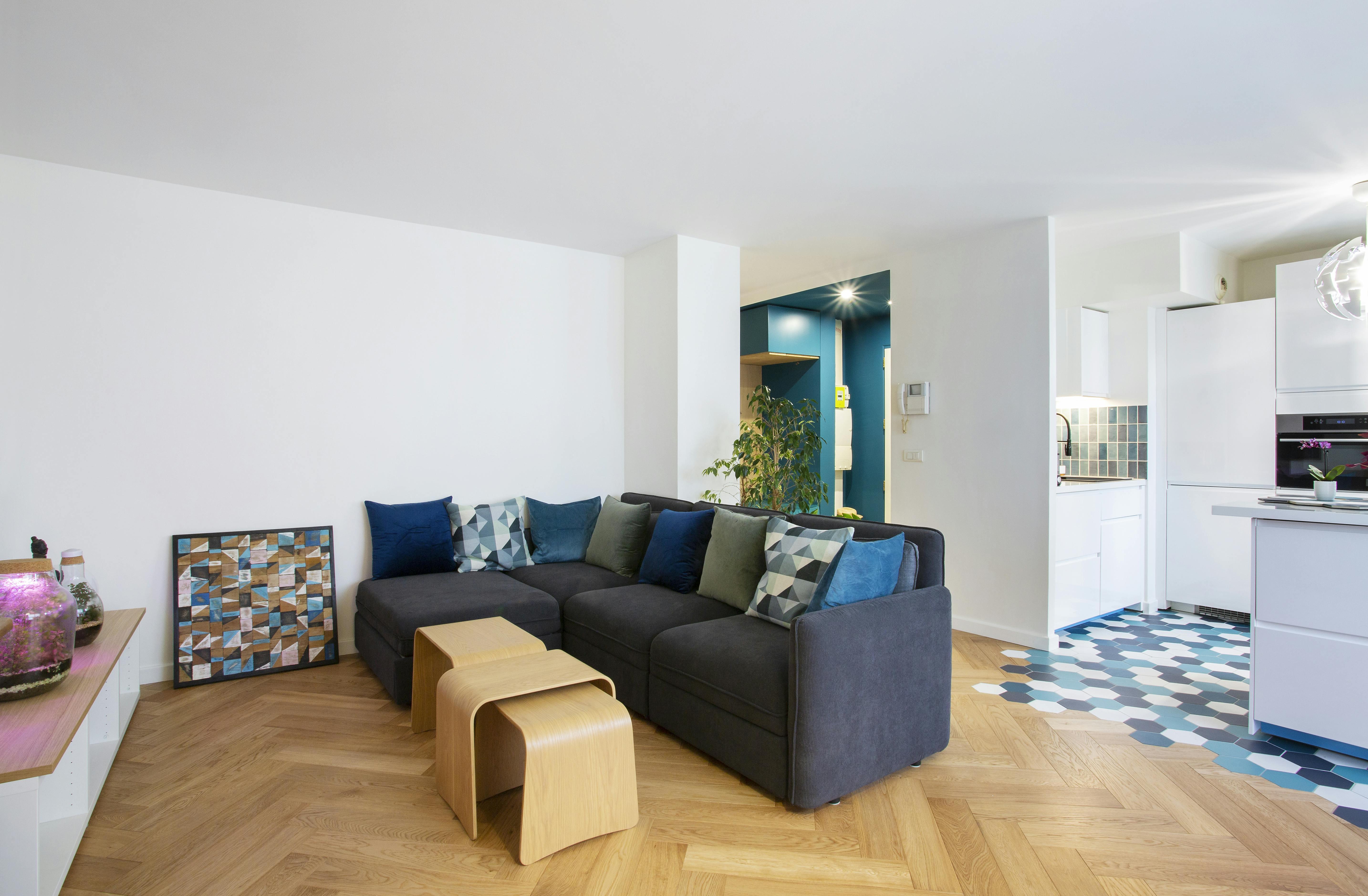 Séjour lumineux avec canapé confortable et parquet en bois.