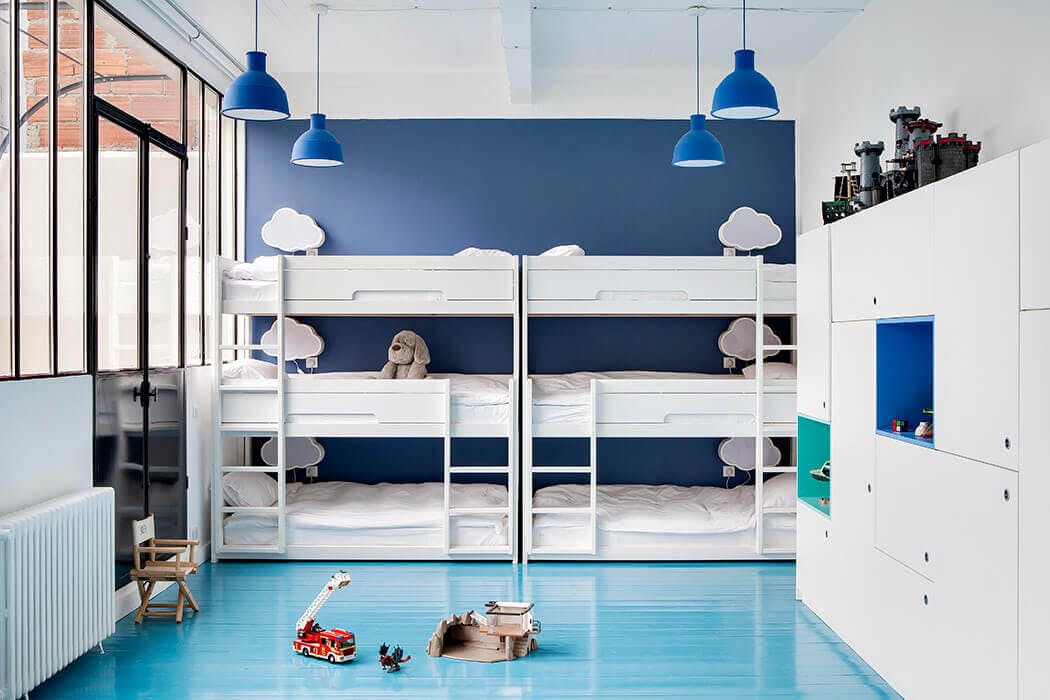 Une chambre d'enfants très épurée avec lits superposés, rangements sur-mesure et verrière.