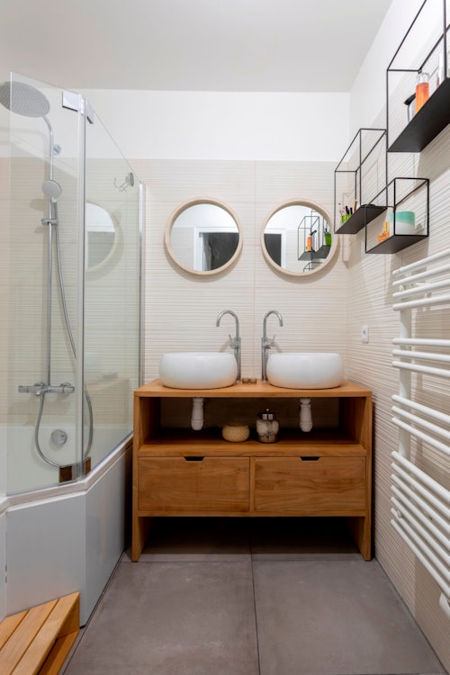 Rénovation de salle de bain dans un style naturel avec dalles de béton au sol et meuble sous vasque en bois