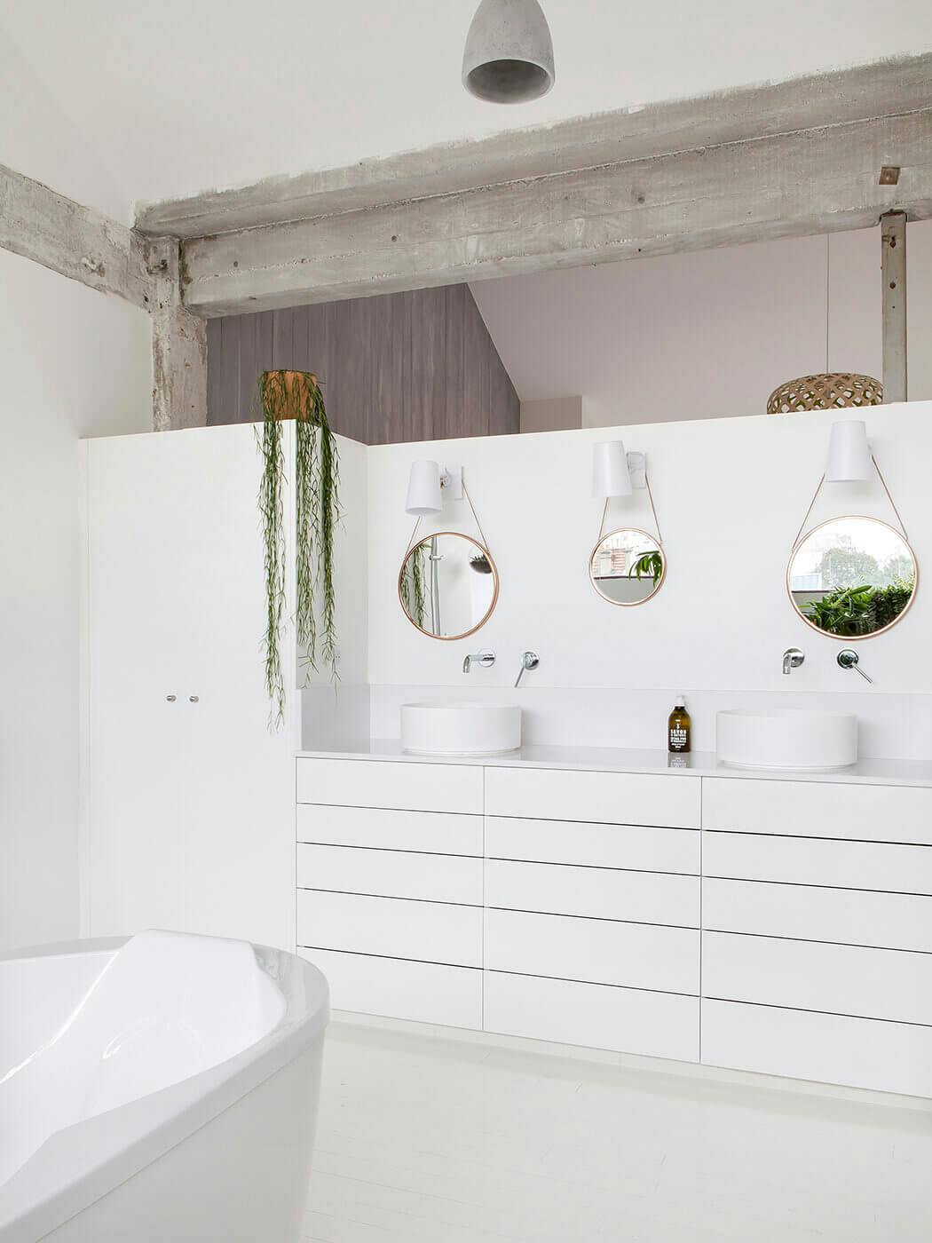 Mélange de modernisme et d'authenticité, avec cette salle de bain au blanc immaculé et ses poutres apparentes