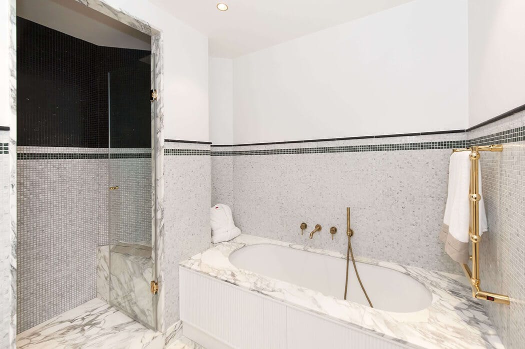 la robinetterie de cette salle de bain de luxe marbre / mosaïque s'associe parfaitement avec le porte-serviette cuivré