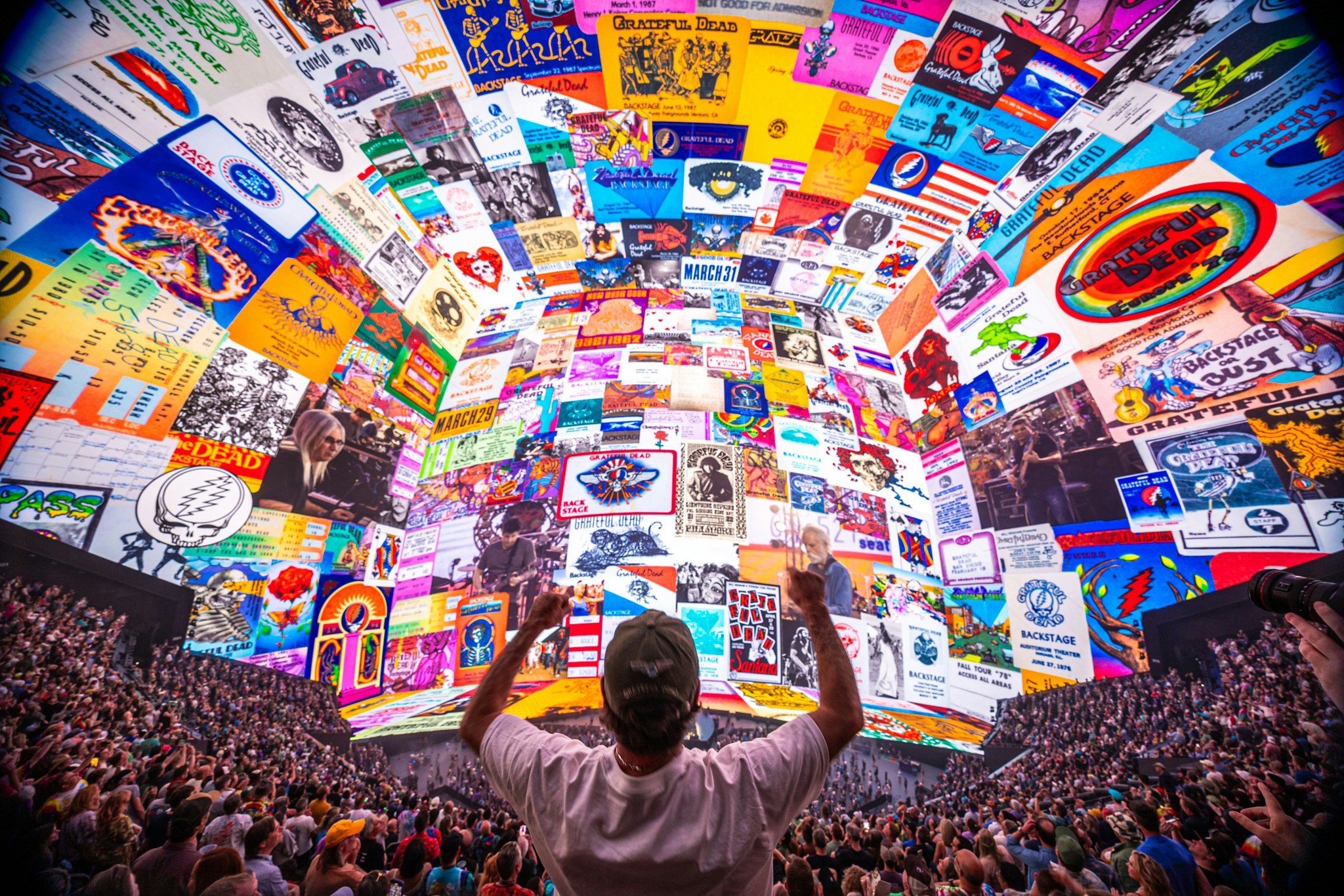 dead and company at sphere, a man raises his arms towards a screen covered in memorabilia from the grateful dead