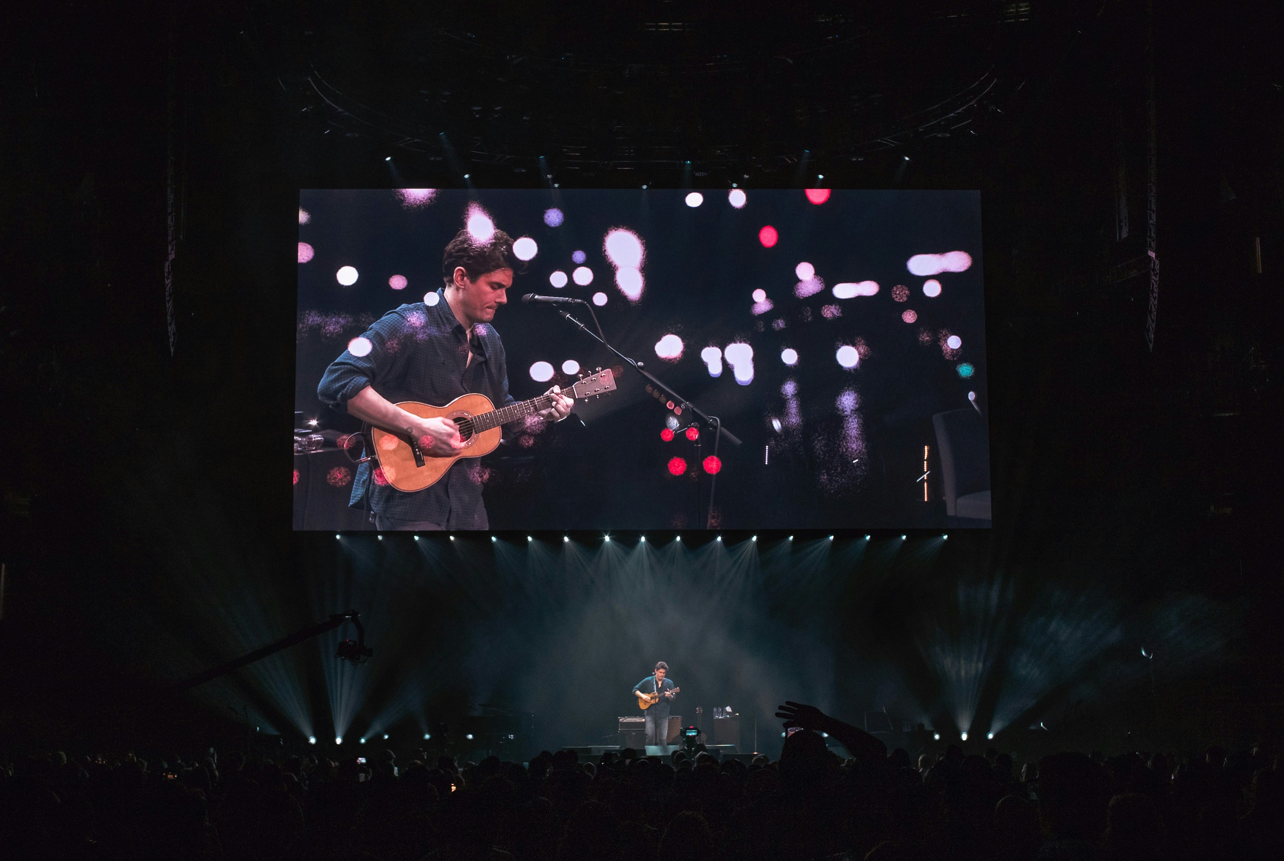 John Mayer stands on stage holding a guitar