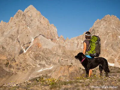 Woman hiking with dog in Teton mountains in Teton Valley Idaho