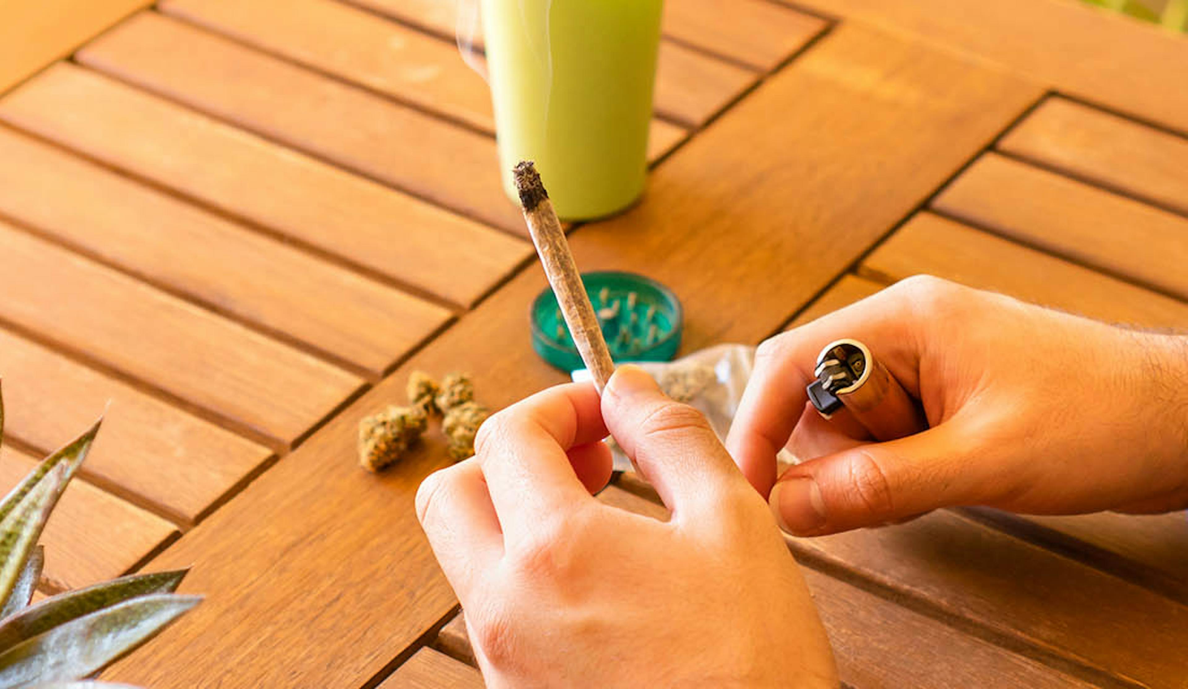 A man holding a partially consumed cannabis joint