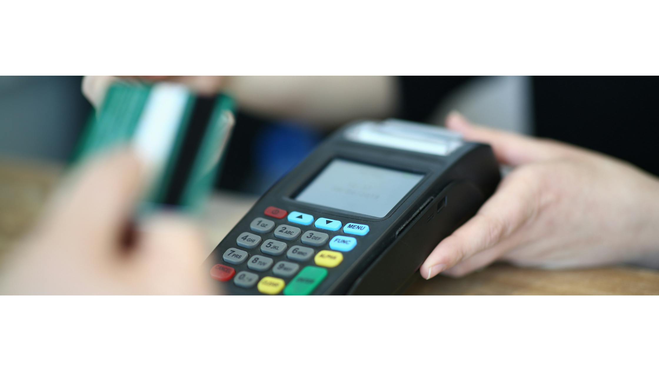 A hand in the foreground prepares a debit or credit card to be inserted into a cashless payments terminal held by a budtender in the background of the image