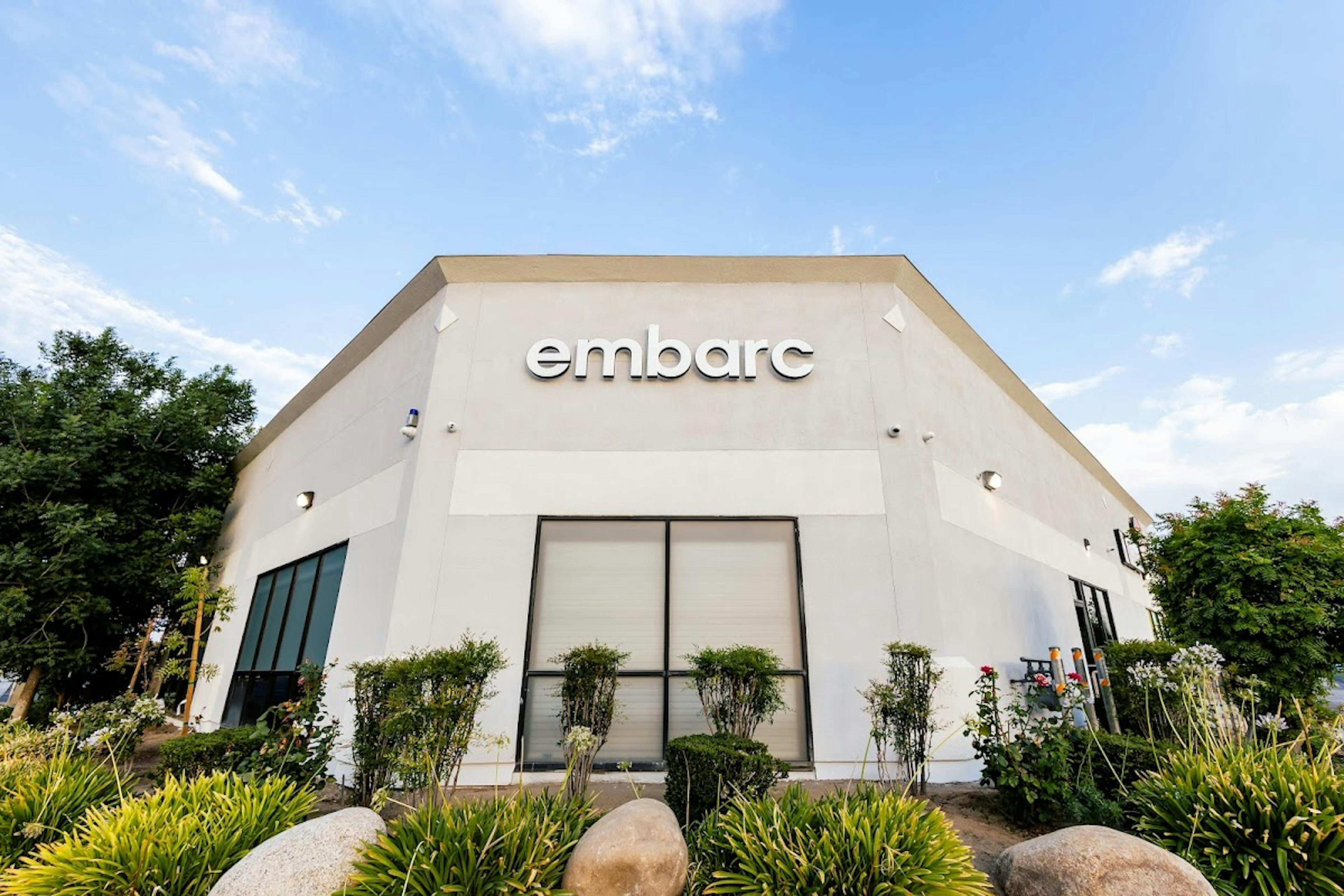Embarc cannabis dispensary storefront in Fresno, California, illuminated by bright sunlight with a clear blue sky backdrop